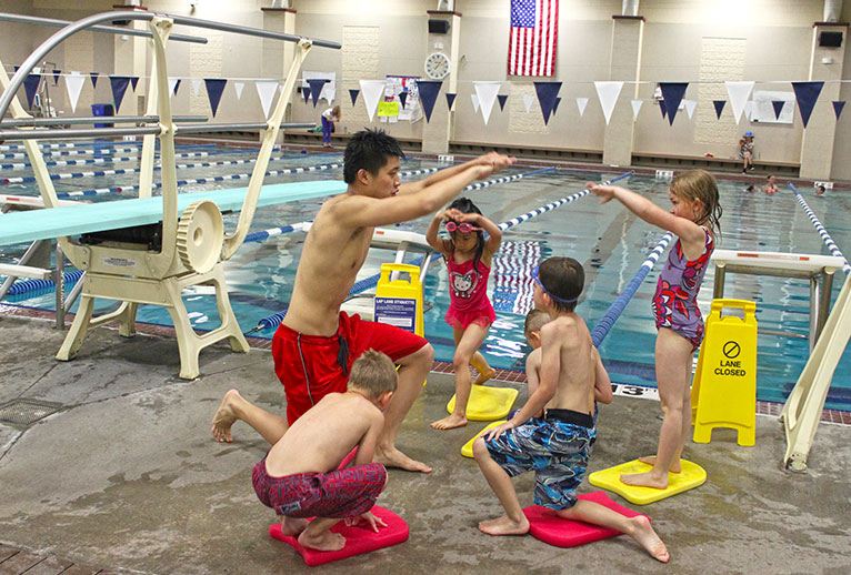 A swimming instructor teaching a group of children.