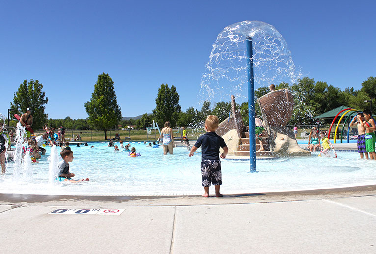Children and playing in an outdoor pool.