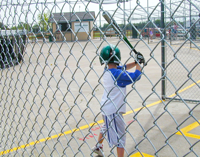 Boy holding a bat at a batting cage.