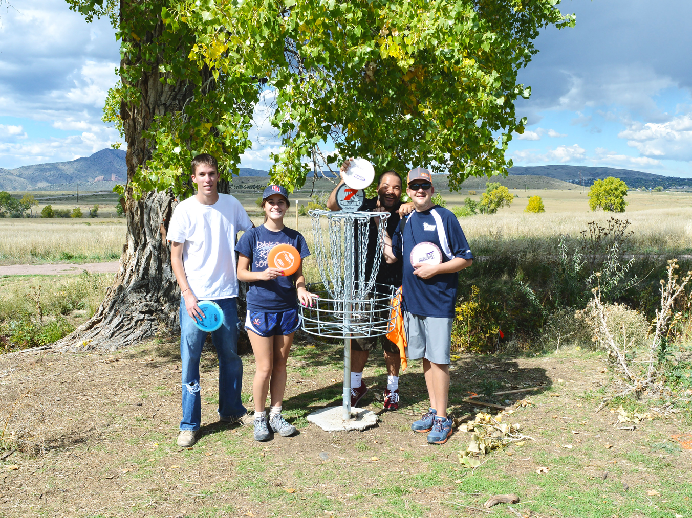 People playing disc golf, holding discs near a basket at Fehringer Ranch Park.
