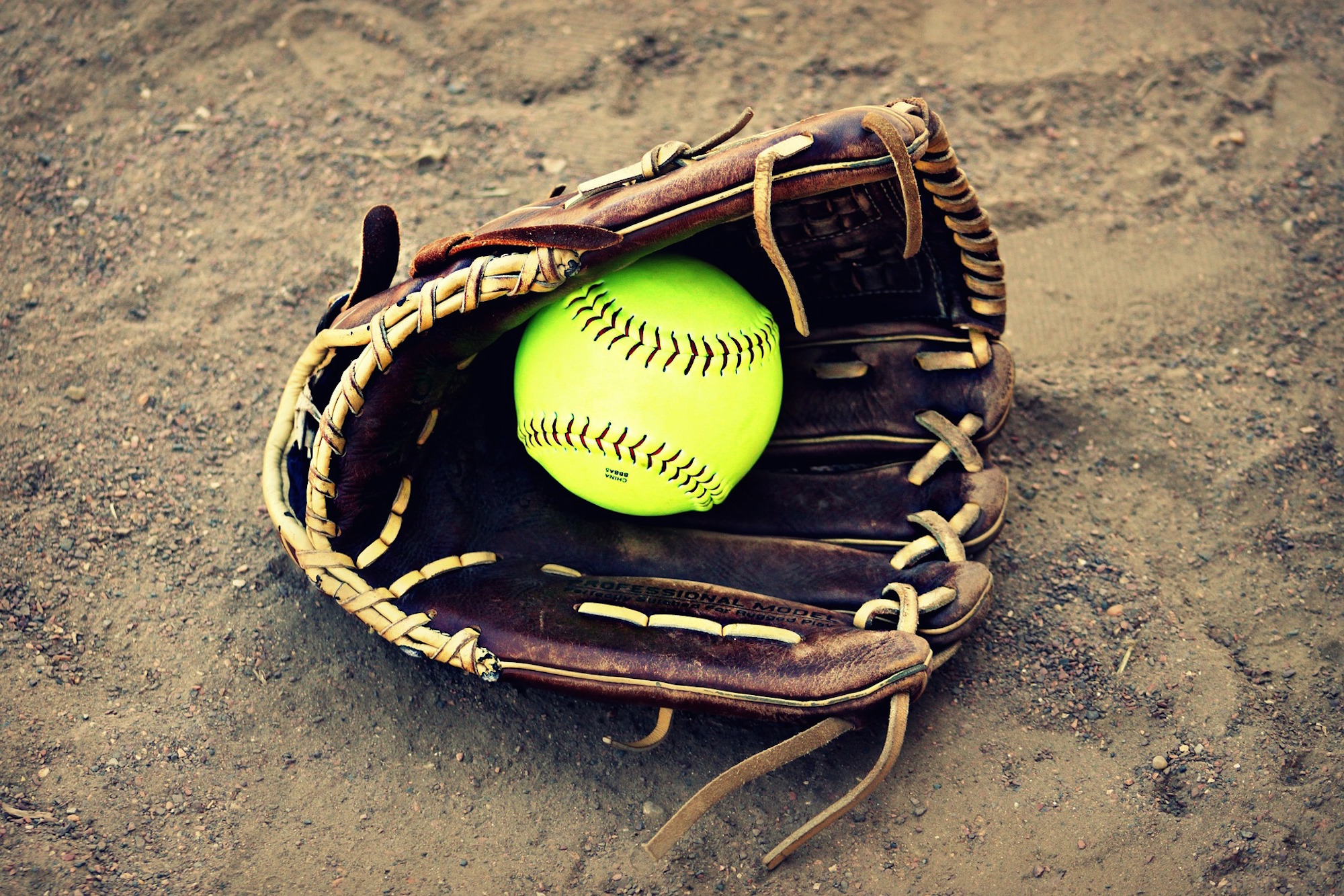 Softball sitting inside a mitt.