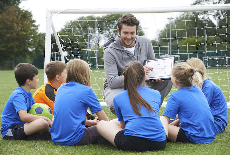 Coach giving team talk to elementary school soccer team