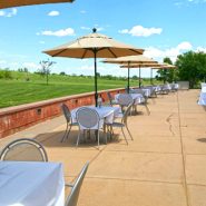 An outdoor patio set up with tables, chairs and umbrellas for a wedding reception.
