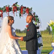 A bride and groom holding hands during their wedding ceremony outdoors.