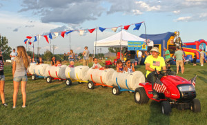 red white & you amusements Children riding in a barrel train at an event.