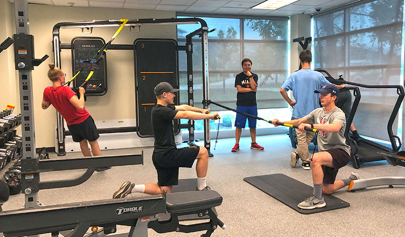 A group of teens in a sport performance training class with a fitness trainer.