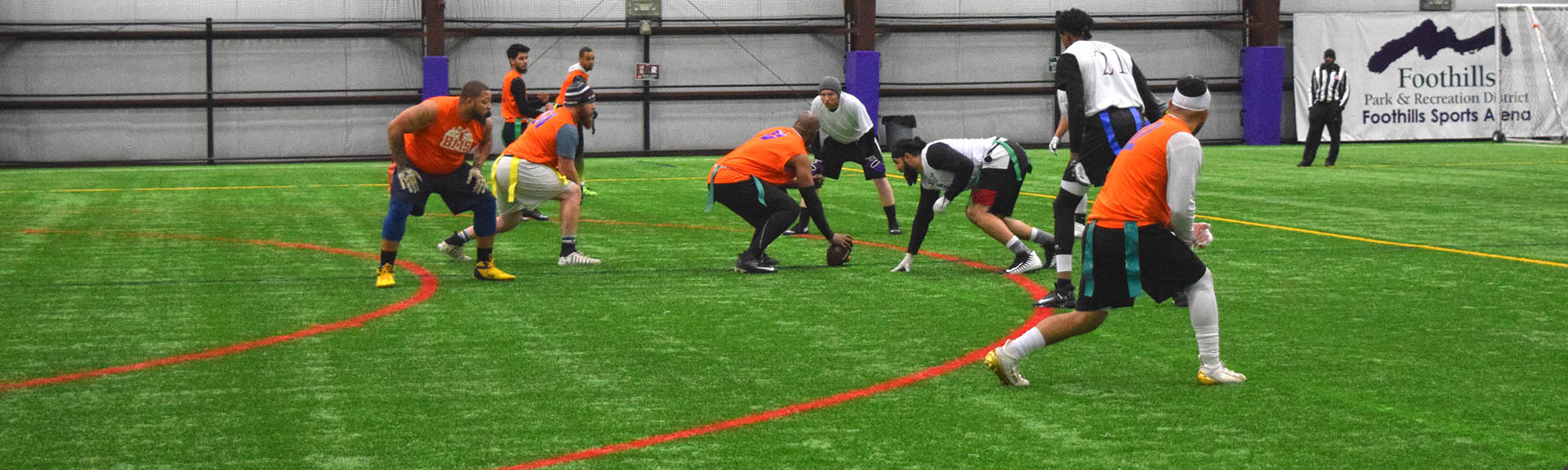 Men's flag football players on an indoor turf field.