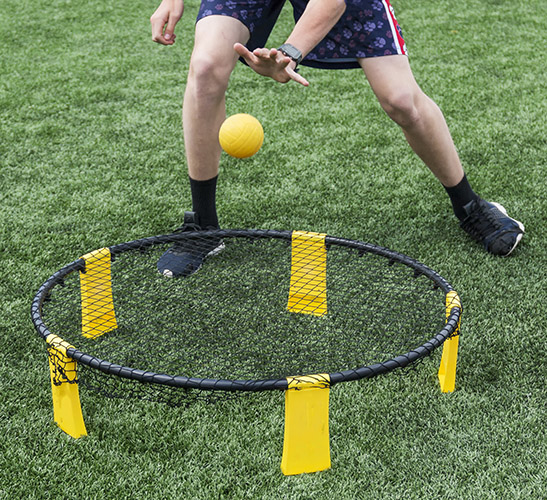 A player is playing spike ball on a green turf field.