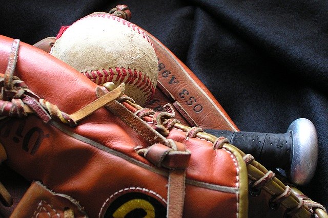 Close up of a softball mitt, ball and bat