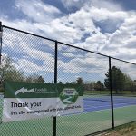 Thank you sign hung on tennis court fencing at Dakota Station Park.