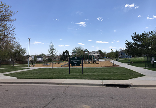 Street view of Trappers Glen Park showing sidewalks, park sign and playground.