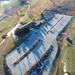 Aerial image of the parking lot at Meadows Golf Club including the clubhouse, driving range and course views.