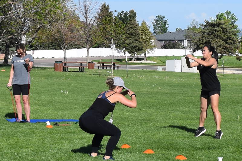 A group of ladies taking a fitness bootcamp outdoors.