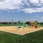 Full playground area with sports fields nearby in the background.