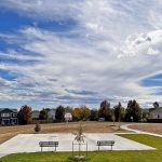 New basketball court and goal with park benches on one side.