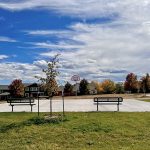 New basketball court and goal with park benches on one side.