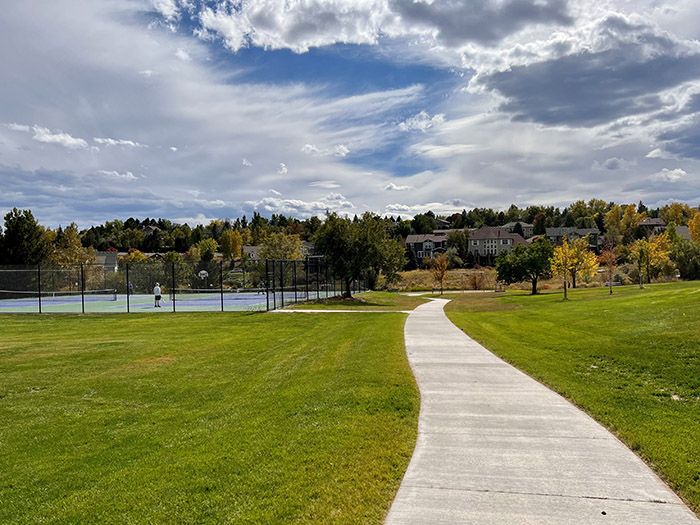 Sidewalk leading to two tennis courts.