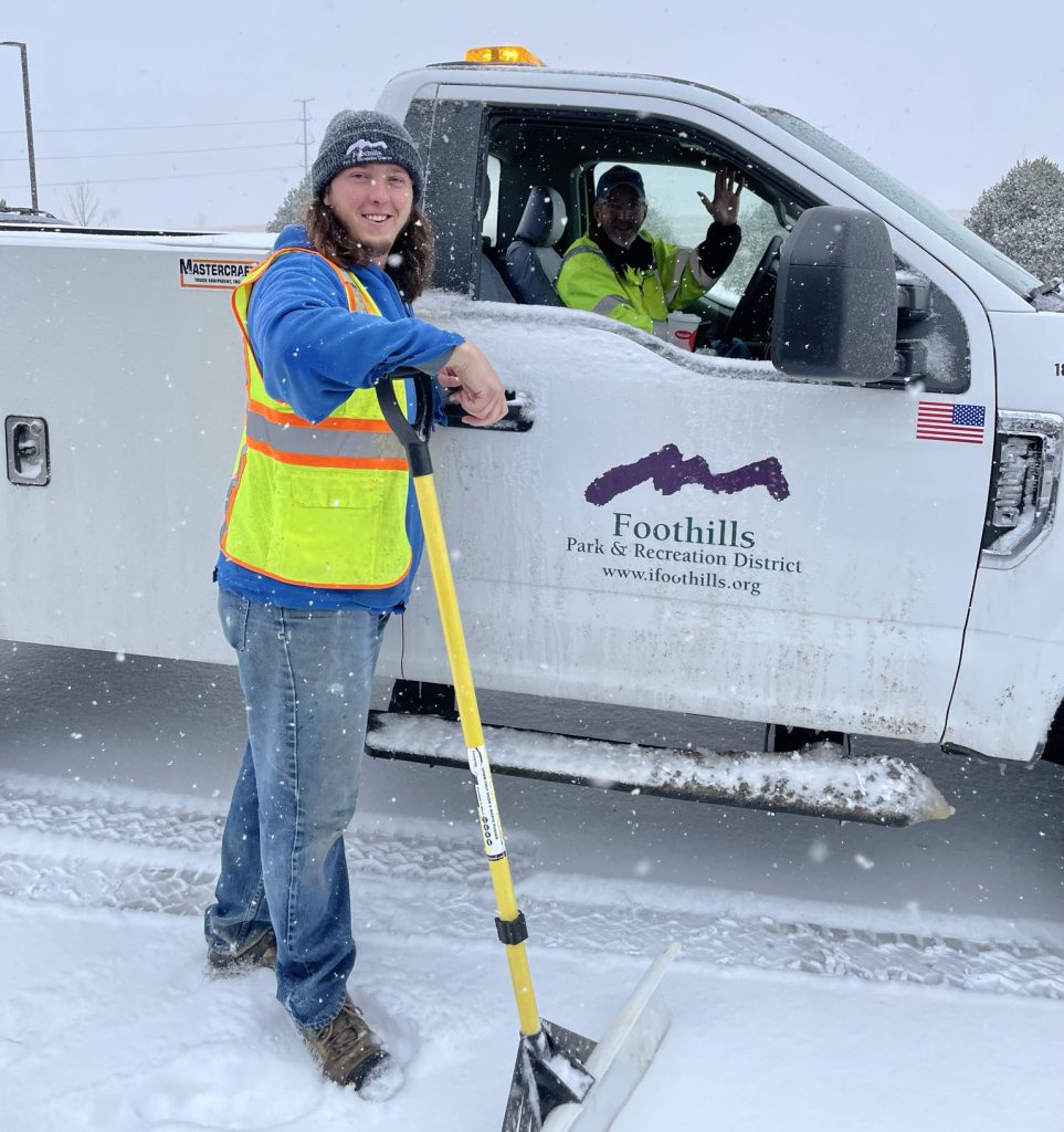 Snow plow and employee shoveling snow