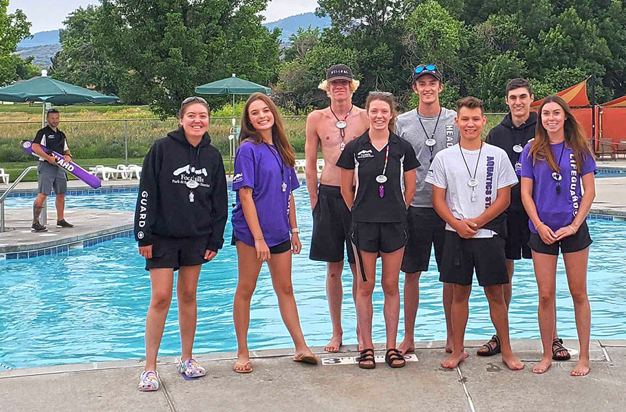 A group of lifeguards standing near an outdoor pool