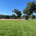 After project shot of Columbine Hills Park with green, groomed grass field and ballfield.