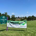 Thank you banner hung off Columbine Sports Park entry sign with green, groomed grass field.