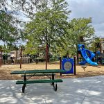 View of playground, swings and picnic table.