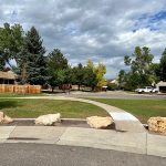 Portions of concrete repairs and large rocks placed alongside the sidewalk curb.