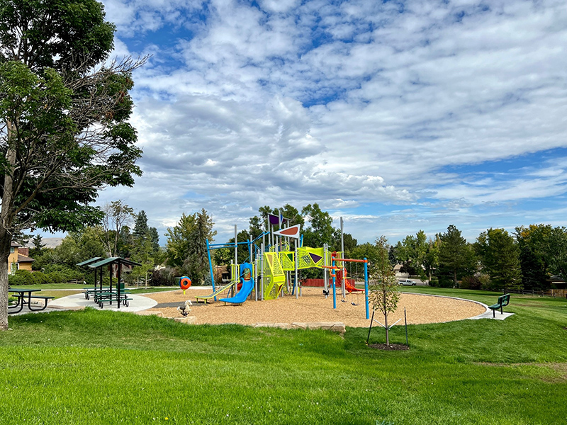 Full view of new colorful playground, park shelters, benches and new tree plantings.