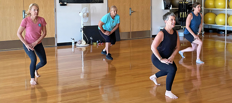 Participants in a fitness class lunging to stretch their quadricep.