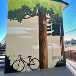 Interactive art piece painted on a wall showcasing a tree with a swing and a bike