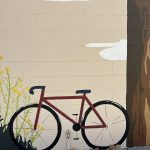 Interactive art piece painted on a wall showcasing a bike, flowers and tree trunk