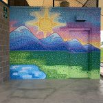 Colorful, painted wall showing the sun starting to set behind the mountains