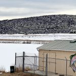 A scenic shot of the shed painted with a rainbow trout with the snow lake and mountains in the background