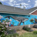 Art installation on the outside of a building displaying an underwater scene with a whale, sea turtle, octopus and ship wreck