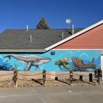 Art installation on the outside of a building displaying an underwater scene with an anchor, whale, sea turtle, octopus and ship wreck