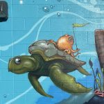 Close up of a section of an art installation on the outside of a building displaying an underwater scene with a small octopus riding on the shell of a sea turtle