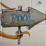 A close up of the artwork displaying a tentacle of the octopus holding an arrow shaped sign that reads the word pool