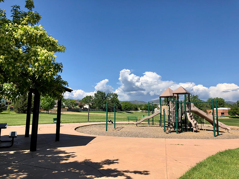 View of a playground with a nearby picnic shelter and mountain in the background