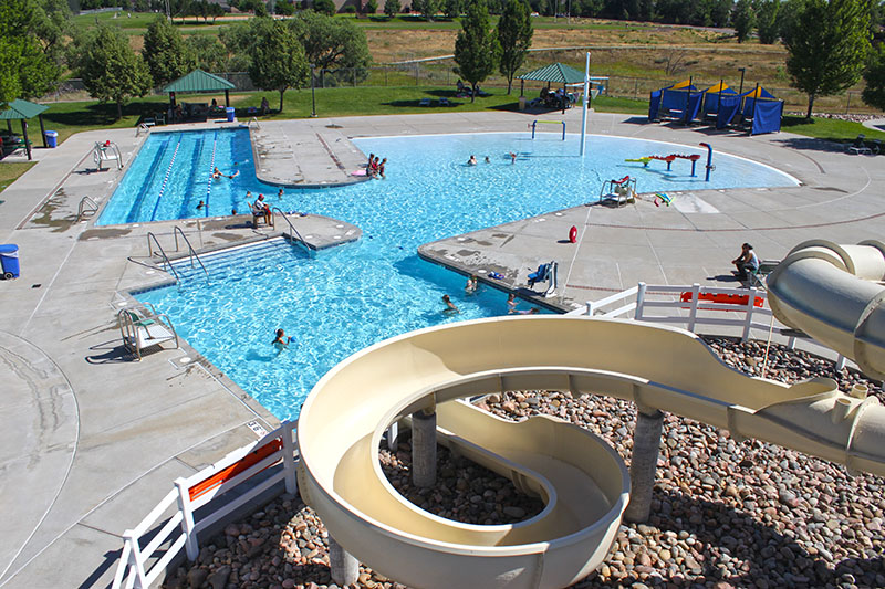 Overhead view of an expansive outdoor pool with play features and a winding slide