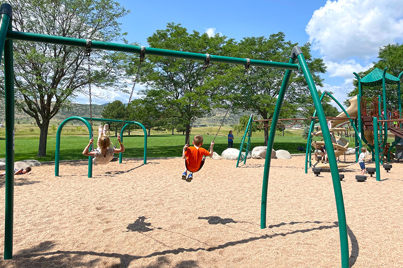 Two kids on swings on the playground in Easton Regional Park