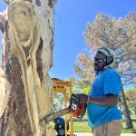Artist Bongo Love carving into a tree using a chainsaw.