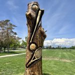 Tree carving artwork showcasing several different sports themed equipment.