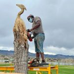 Artist Bongo Love begins to carve into a tree using a chainsaw.