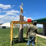 Artist Bongo Love steps back to review his tree carving art of a blue heron.