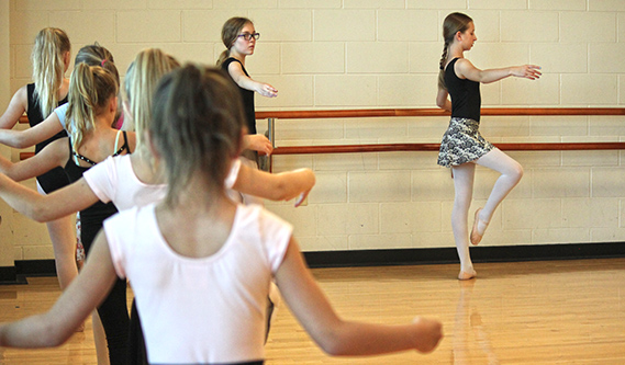 A group of youth in a ballet class doing warm up exercises