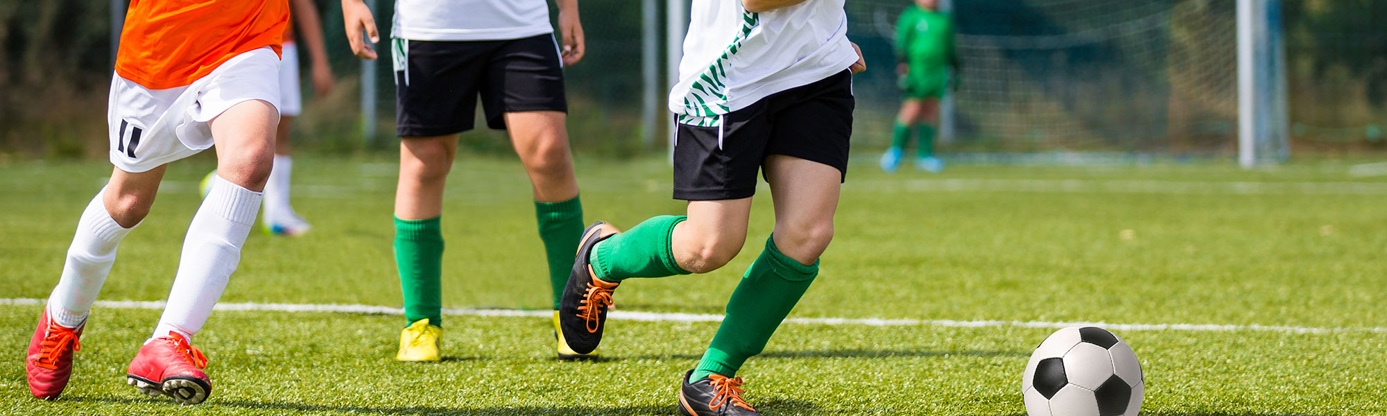 Soccer players running toward a soccer ball