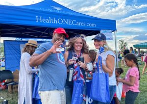 A group of event attendees visiting a sponsor booth at the Red, White & You event.