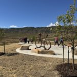 Metal art installation of a biker off the Dutch Creek Trail with people walking in the background.