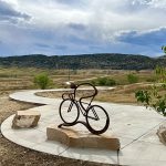 Iron sculpture of a person on a bicycle mounted on a large rock near the Dutch Creek Trail.