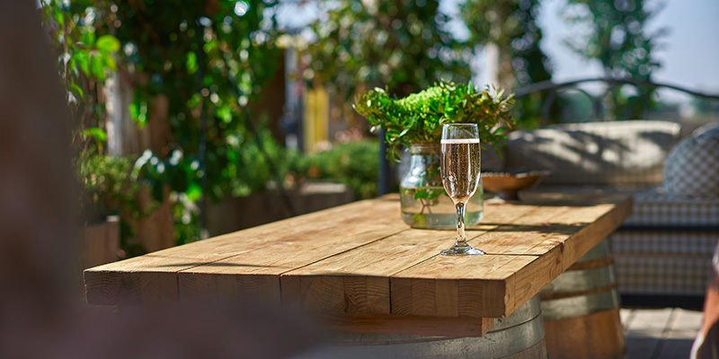 Cozy terrace with sofas for rest, Glass with champagne on a wooden table.